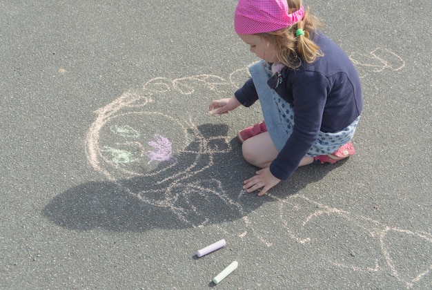 분필로 포장 도로에 화창한 날과 어머니 아기 소녀를 그립니다.
