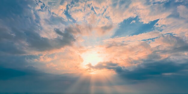 Sunny evening sun at the horizon and yellow clouds on blue sky