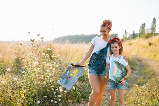 Sunny nature, mom and daughter paint a picture in a park , painting a Little Child, Child Creativity.