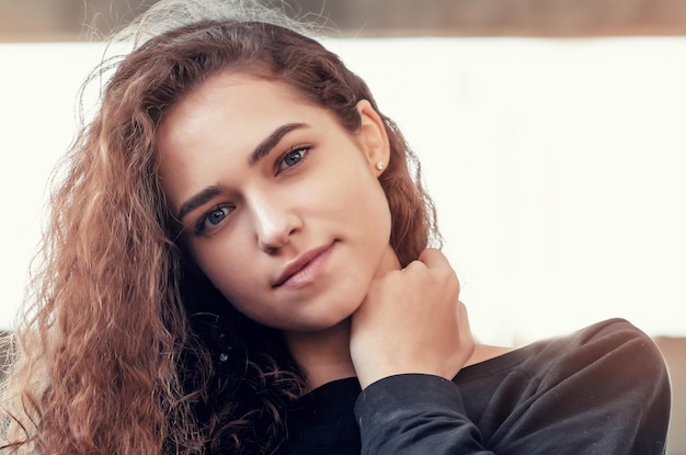 Sunny portrait of a beautiful curly girl look at the camera