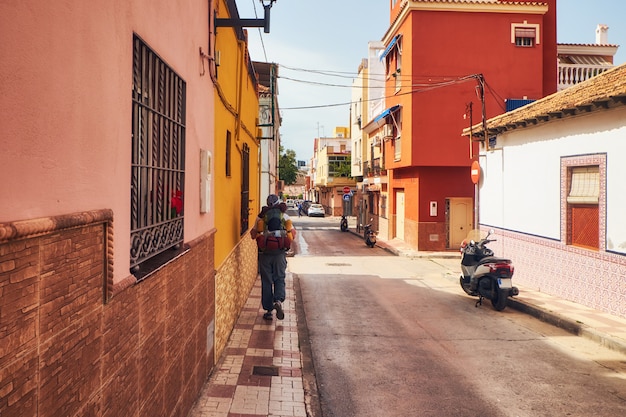 Sunny street on the outskirts of Malaga and tourist walking away with backpack. Andalusia. Spain