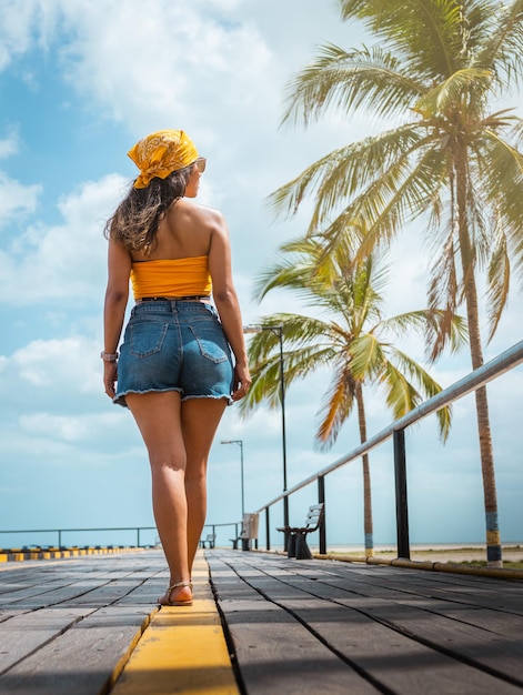 Foto sunny stroll donna latina che cammina sul molo della spiaggia circondato da palme