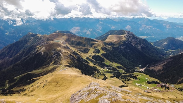 Valle soleggiata tra maestose colline verdi e nuvolose di montagna ricoperte di erba e cespugli verdi e lussureggianti