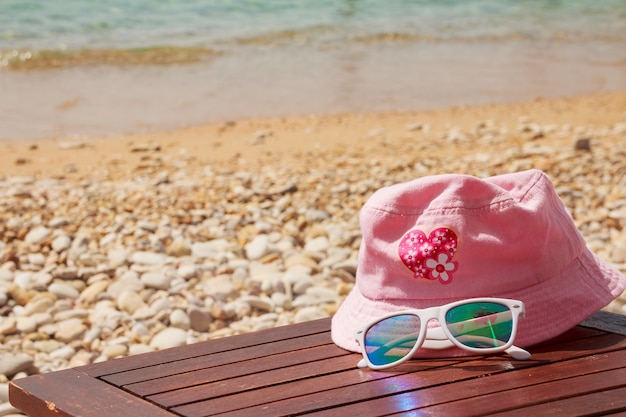 Oggetti di protezione solare sulla spiaggia in vacanza occhiali da sole e cappello bianco