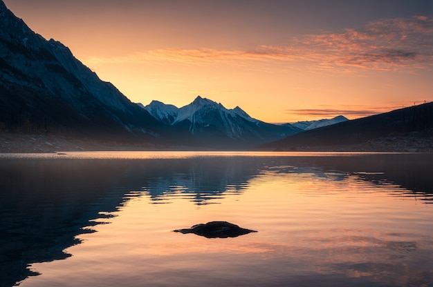 Sunrise on Canadian rockies with rocks on Medicine Lake at Jasper national park