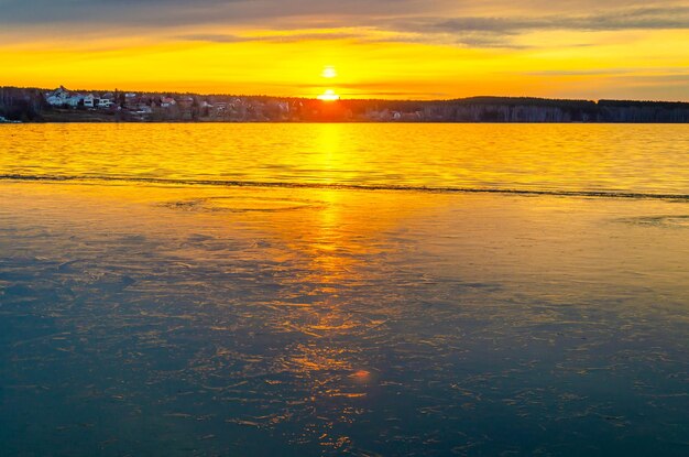 凍った湖に昇る朝日。