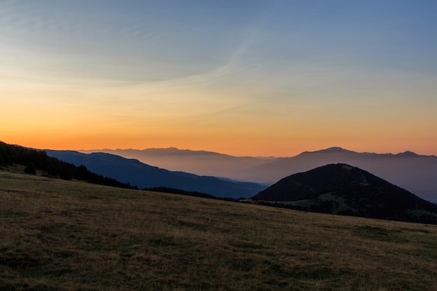 Alba da una valle a guardare le montagne con un po 'di nebbia.