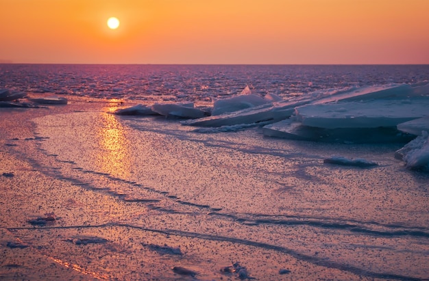 Sunrise and frozen sea Beautiful winter landscape with lake and red sun in morning time Daybreak