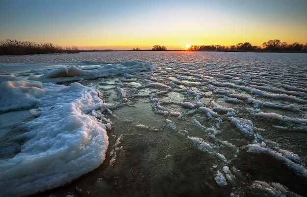 日の出と凍った海の海岸 朝の時間に湖のある美しい冬の風景