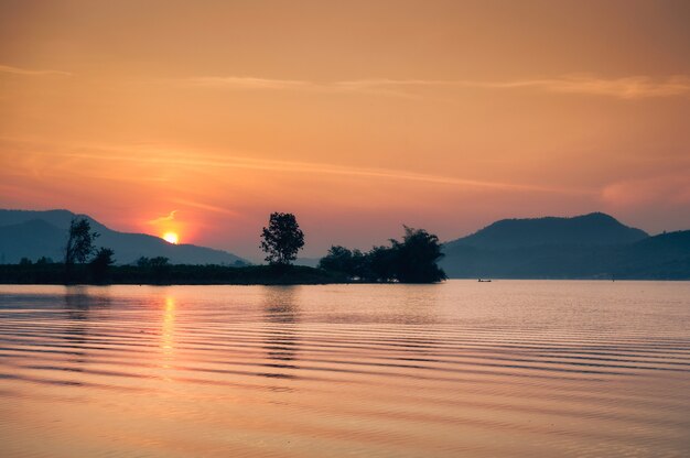 Sunrise over mountain range on Lam Taphoen reservoir in countryside at Suphanburi, Thailand