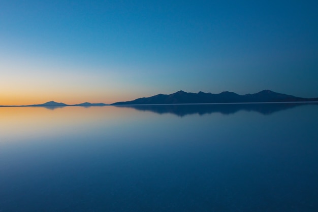 Sunrise on Salar de Uyuni in Bolivia covered with water, salt flat desert and sky reflections