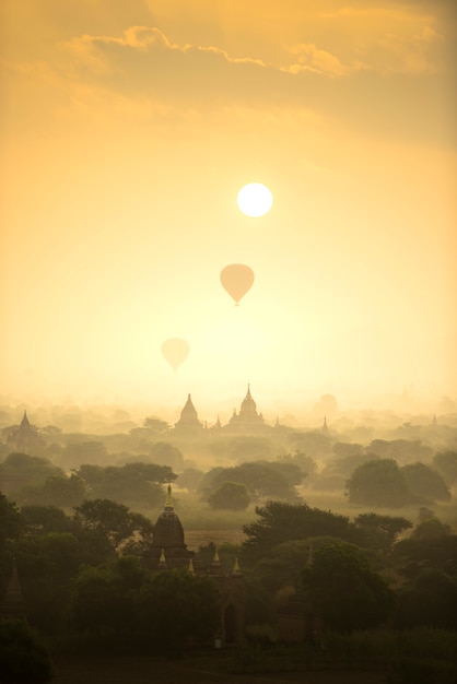 Sunrise scene hot air balloons fly over pagoda ancient city field in Bagan Myanmar.