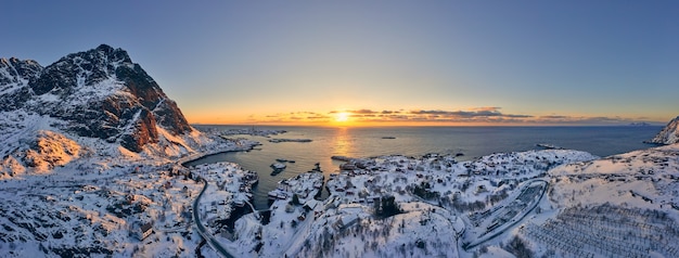 Sunrise over the sea illuminating a small Norwegian fishing village. Breathtaking aerial view.