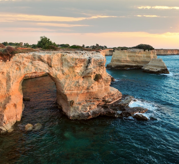 Sunrise seascape with cliffs rocky arch and stacks faraglioni at Torre Sant Andrea Salento sea coast Puglia Italy