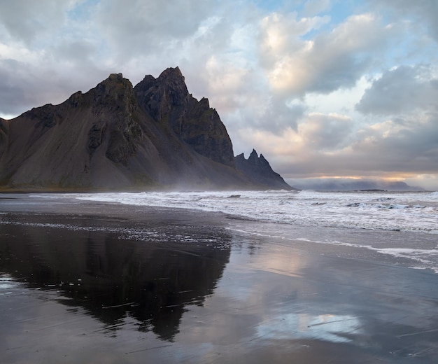 Фото Восход солнца на морском пляже на мысе стокснес и гора вестрахорн с ее отражением на влажной черной поверхности вулканического песка исландия удивительная природная пейзажа популярное место для путешествий