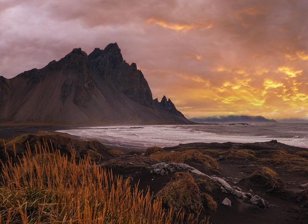 Sunrise Stokksnes cape sea beach and Vestrahorn Mountain Iceland Amazing nature scenery popular travel destination Autumn grass on black volcanic sand dunes