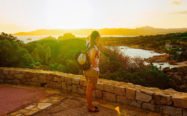 Sunrise or sunset and young girl at Baja Sardinia of Costa Smeralda at Mediterranean sea in Sardinia island in Italy. Woman and Sardegna in summer.