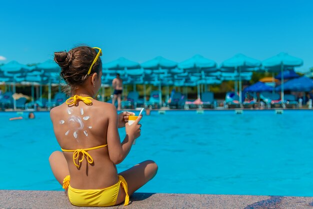 Sunscreen on the back of the child. Selective focus.