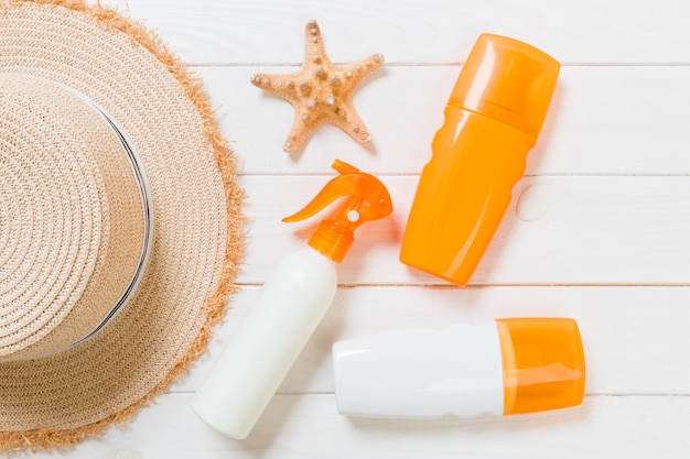 Photo sunscreen bottles with starfish and sunhat on white wooden table with copy space. travel healthcare accessories top view.