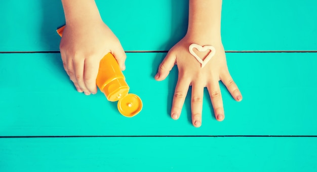 Crema solare sulla mano di un bambino.