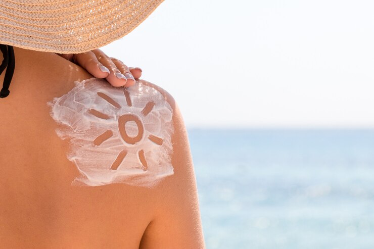 Photo sunscreen lotion in sun shape on tanned woman's shoulder