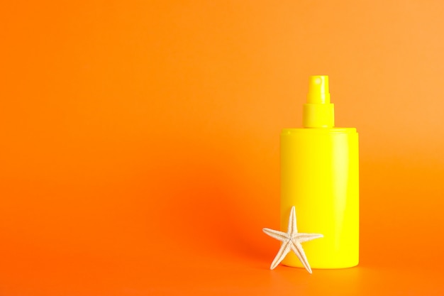 Sunscreen spray with starfish on color background