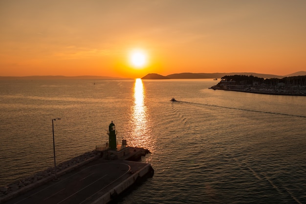 アドリア海に沈む夕日と、クロアチアのスプリット港の入り口で反射するボートで遊んでいます。