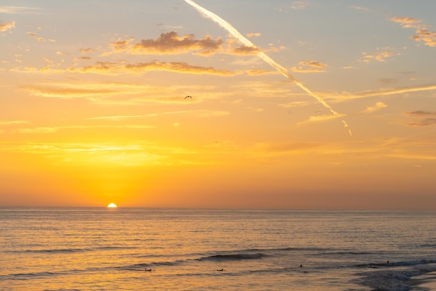 Sunset against the background of the Pacific Ocean. Pink clouds in the blue sky.