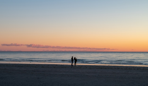 海に沈む夕日、海と同じ高さの太陽、そしてカジュアルな通行人