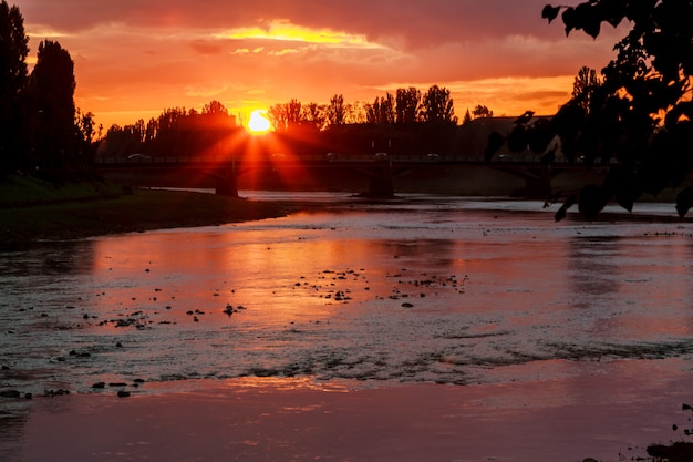 川の川岸の夕日ウズゴロドウクライナの背景に夕日
