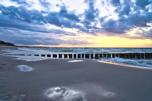 Sunset on the beach of the Baltic Sea Reflection on the beach Groynes reach into the sea