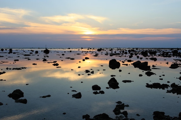 Tramonto sul paesaggio marino panoramico della spiaggia con roccia durante la bassa marea