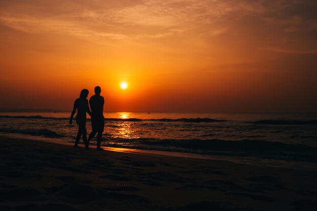 カップルのシルエットとビーチの夕日