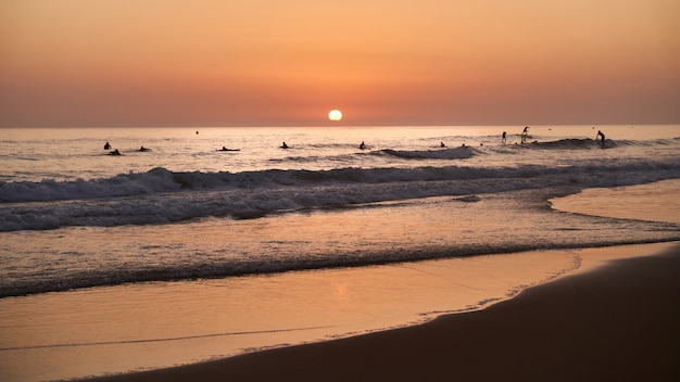 Sunset on the beach with surfers in the water