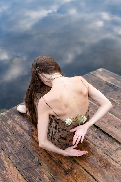 At sunset a beautiful sexy girl of Caucasian appearance sits on the river bank