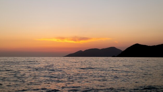 海の曇り空に沈む夕日