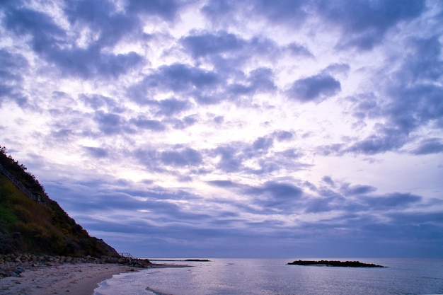 デンマークの海岸に沈む夕日 浜辺の波 背景の木のある丘 風景