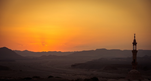 前景のイスラム教徒のモスクと砂漠の上の夕焼け