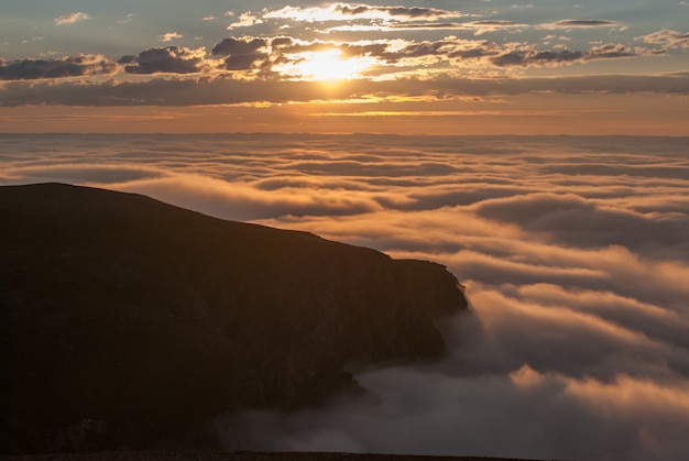 ノルウェー、セール島の岩の上の霧に沈む夕日