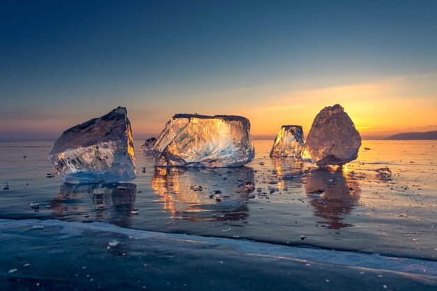 Foto il tramonto sul lago ghiacciato del paesaggio di baikal la luce solare è rifratta in pezzi di ghiaccio