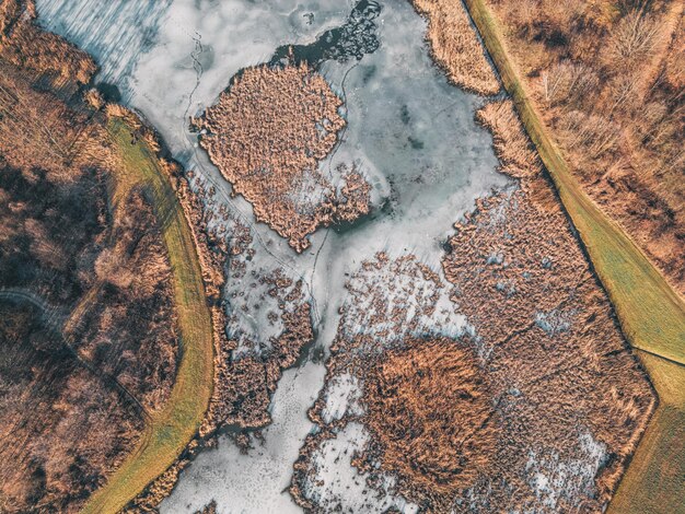 Photo sunset over a frozen lake a sheet of ice covered with animal tracks and frozen grass