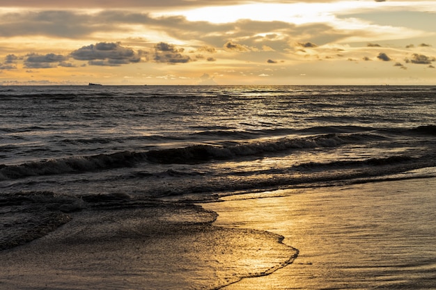 Sunset golden hour in the sea beach with waves and sun reflection