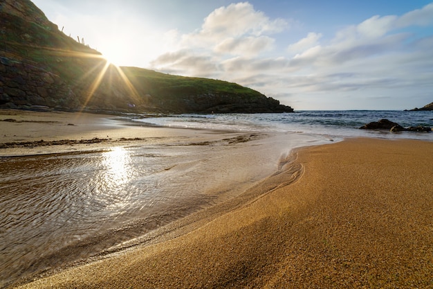 Tramonto sulla spiaggia di sabbia dorata con piccole pozze d'acqua che riflettono il sole santander