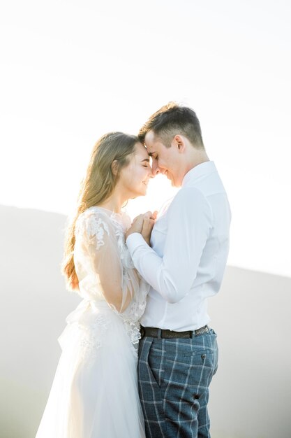 Sunset illuminates mountain hill where wedding couple walks