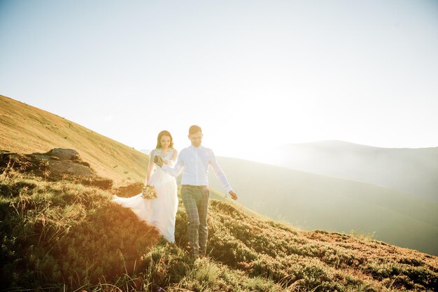 夕日は結婚式のカップルが歩く山の丘を照らします