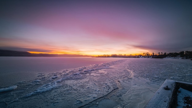 a sunset is shown on a frozen lake with a sunset in the background