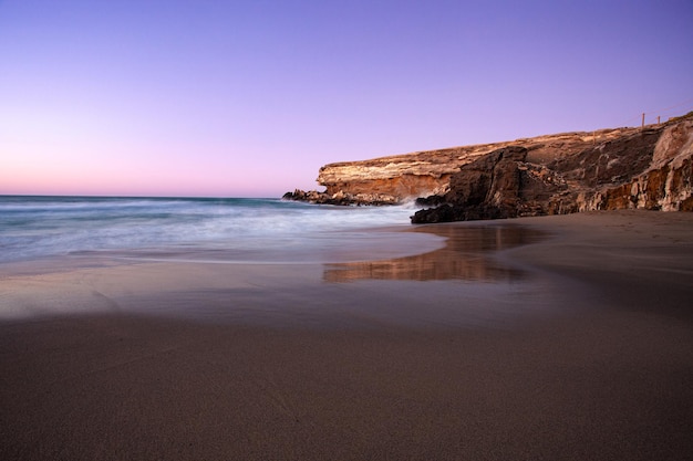 sunset at la pared volcanic beach, south of Fuerteventura, with reddish rock and sea