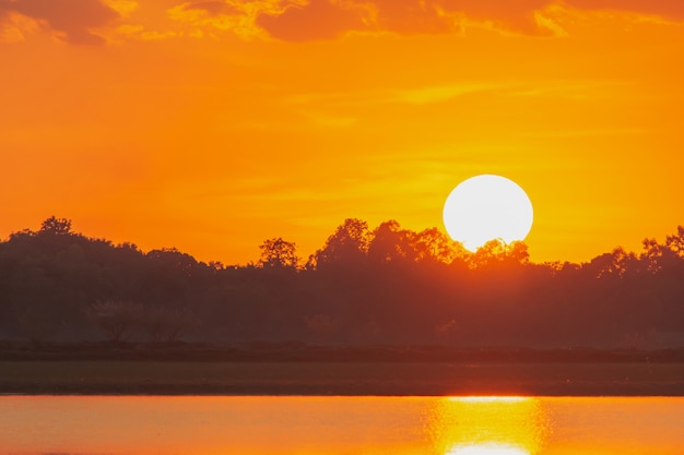 湖の夕日。湖の風景以上の背景の上の雲の後ろに美しい夕日。夕焼け雲と劇的な空