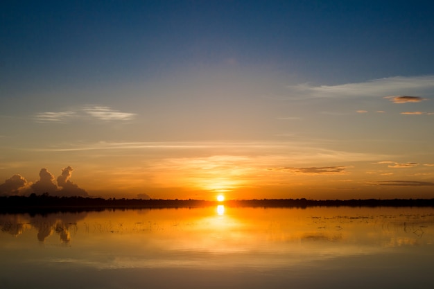 Sunset in the lake. beautiful sunset behind the clouds above the over lake landscape background.