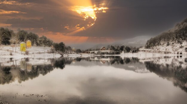 a sunset over a lake with a mountain in the background